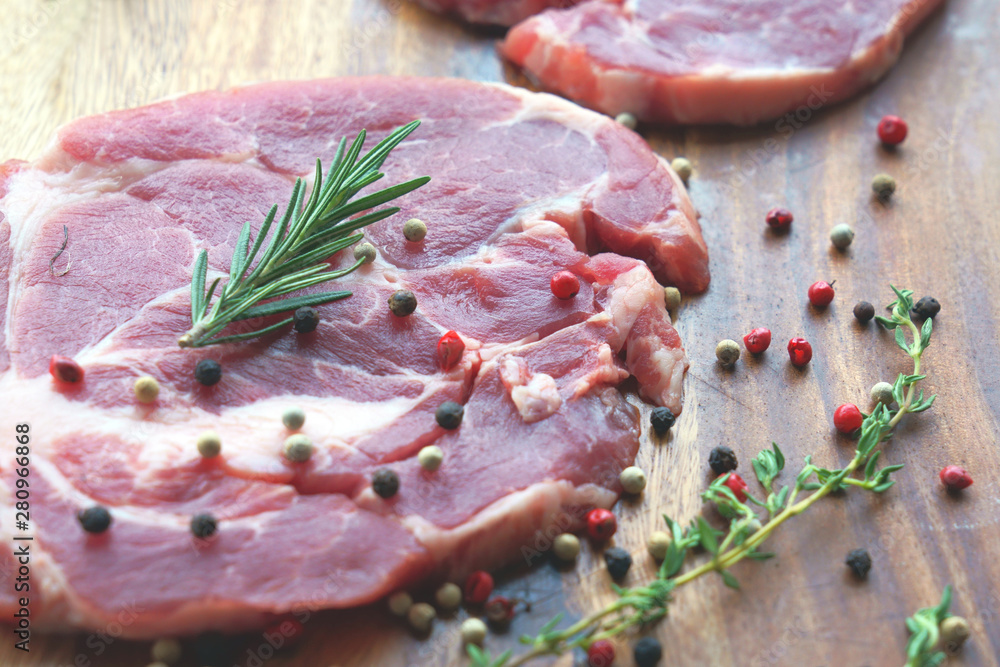 Close up of uncooked raw meat with rosemary and pepper on wooden background
