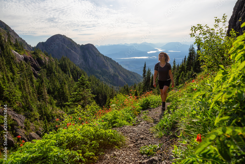 Adventurous girl hiking the beautiful trail in the Canadian Mountain Landscape during a vibrant summer evening. Taken at Mt Arrowsmith, near Nanaimo, Vancouver Island, BC, Canada.