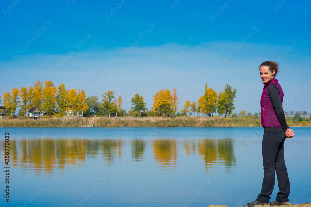 Beautiful young woman enjoying autumn by the side of a wild lake Beautiful young woman enjoying autumn by the side of a wild lake