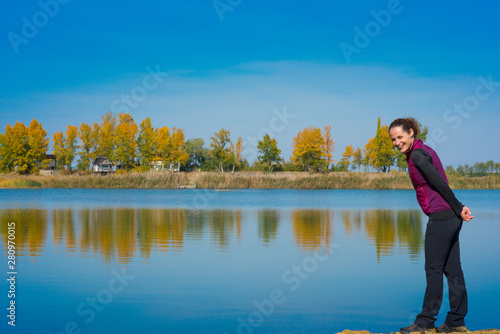 Beautiful young woman enjoying autumn by the side of a wild lake