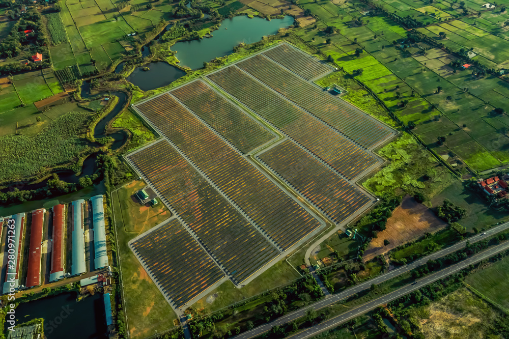 Obraz premium Aerial view of solar cell panel in countryside landscape with traffic asphalted parallel road and a fields 