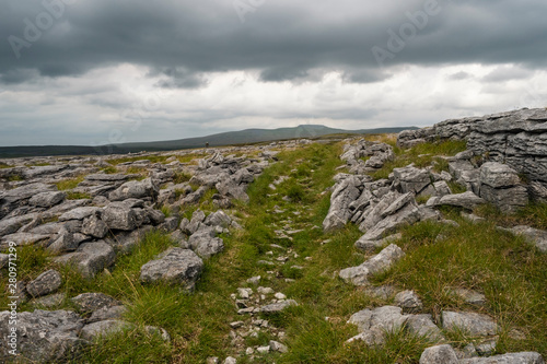 Moughton Scar is a vast and impressive limestone pavement full of interesting nooks and crannies. In the distance a moody Pen-y-ghent is seen in profile. © RamblingTog