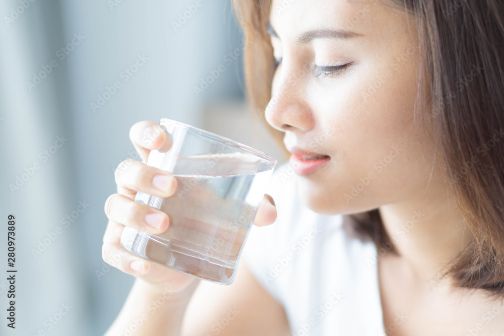 Close up woman drinking pure water from glass with light in the morning, Selective focus Close up woman drinking pure water from glass with light in the morning, Selective focus