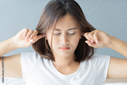 Closeup woman covering ears with her hand, noise problem, selective focus