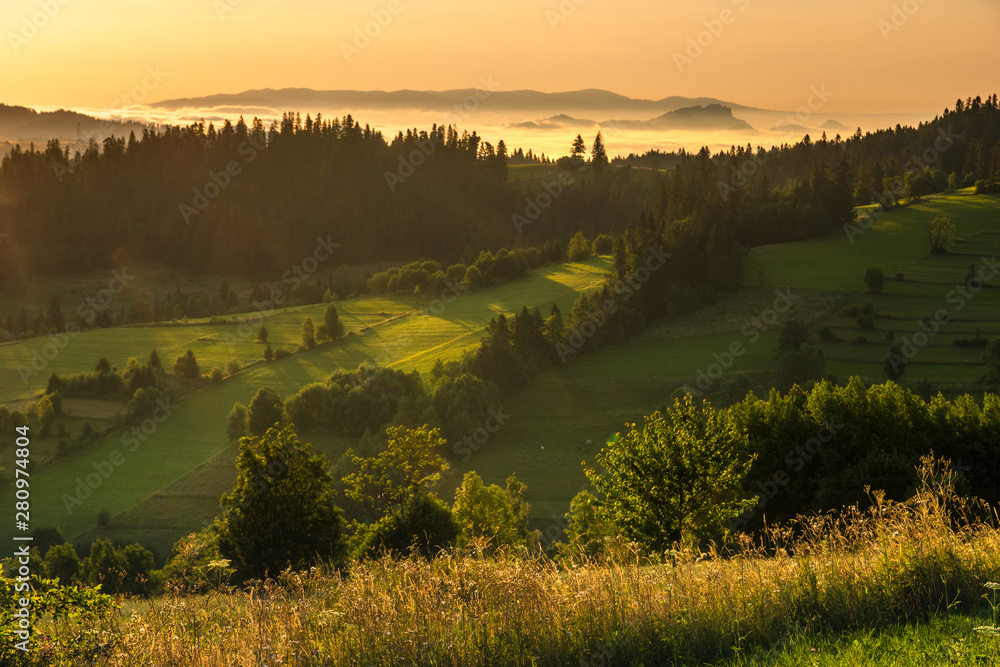 A beautiful mountain view. Mountains and green hills emerging from the morning mists illuminated by the rising sun. A view from the top of the Czarna Góra mountain in Poland