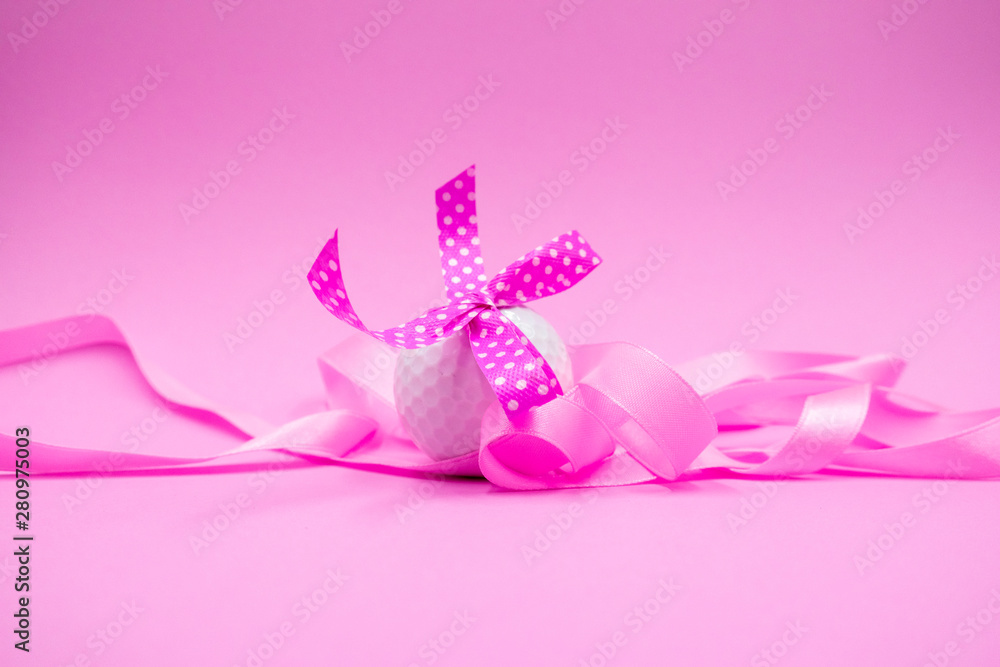 Golf ball with pink ribbon is on pink background Golf ball with pink ribbon is on pink background