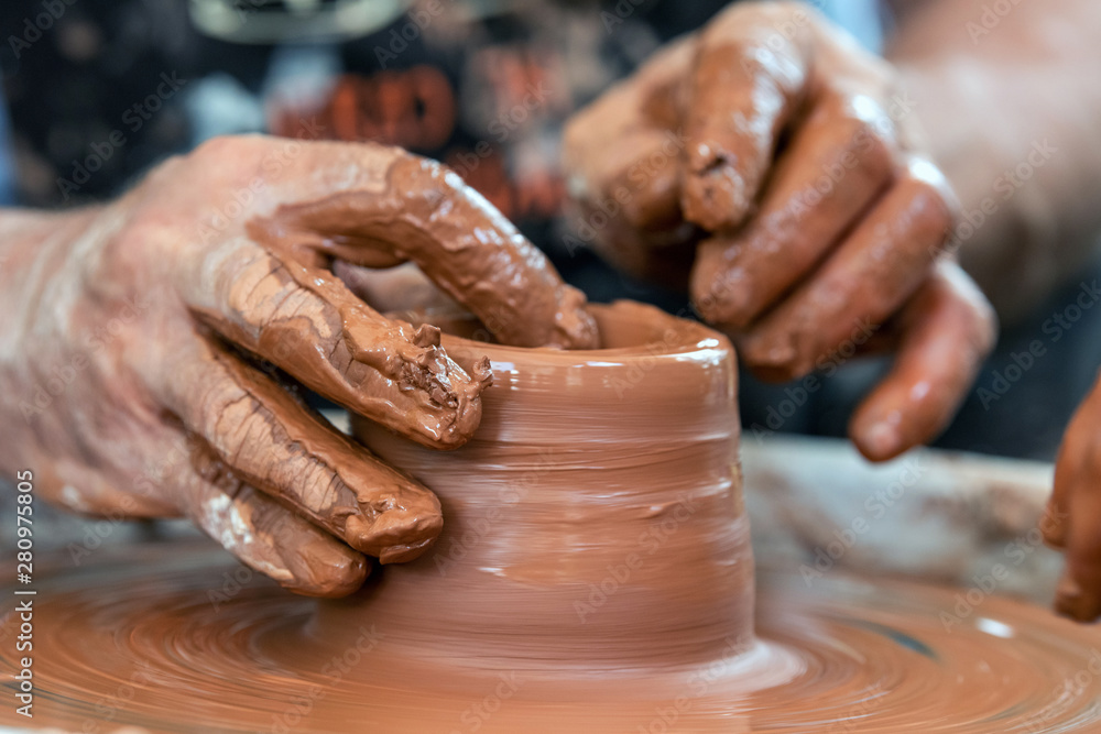 Potter makes pottery dishes on potter's wheel