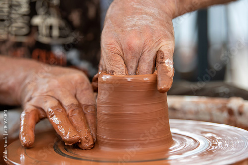 Potter makes pottery dishes on potter's wheel