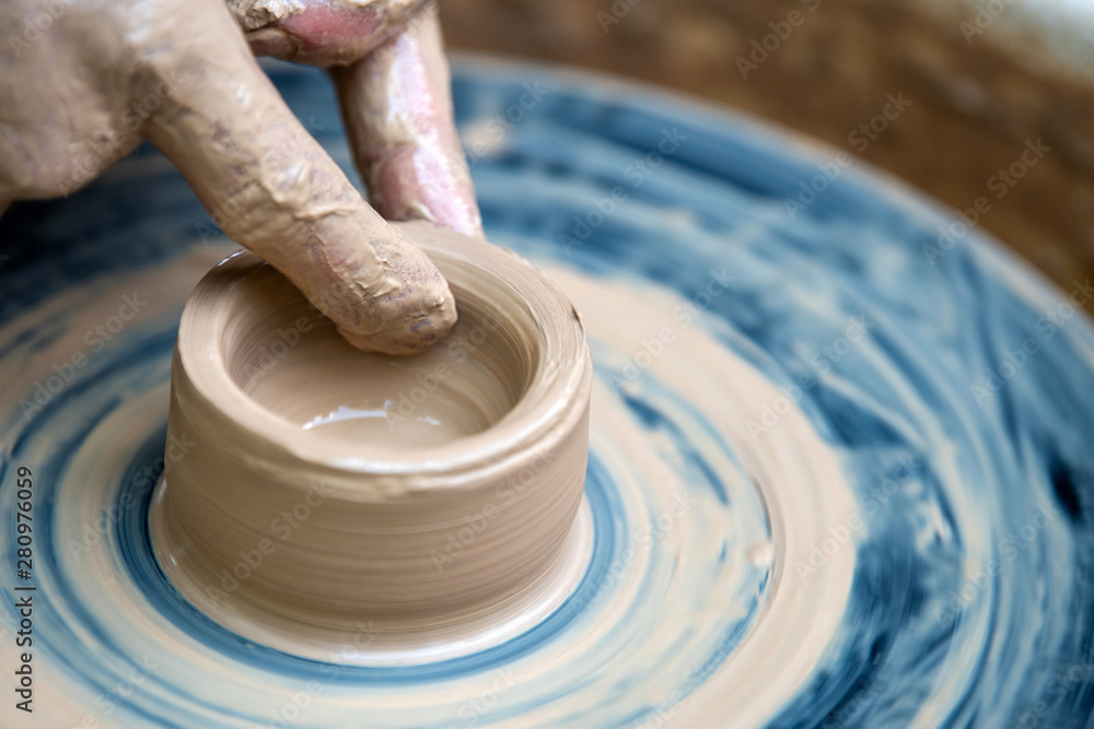 Fototapeta premium Potter makes pottery dishes on potter's wheel