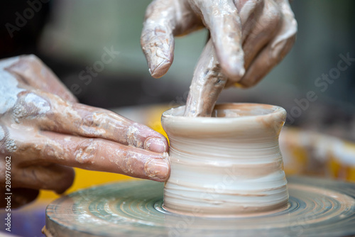 Potter makes pottery dishes on potter's wheel