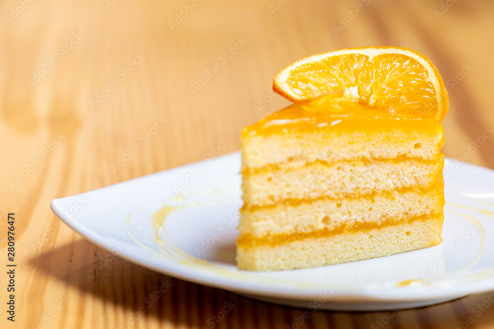 Orange cake with orange topping on wooden table in coffee cafe Orange cake with orange topping on wooden table in coffee cafe