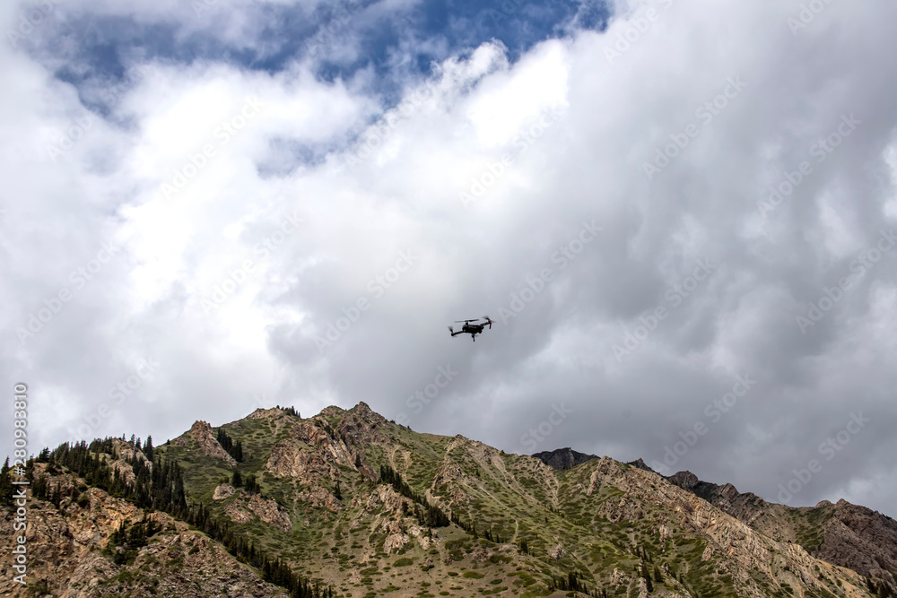 Drone in the cloudy sky over a mountain range. Traveling in Kyrgyzstan Drone in the cloudy sky over a mountain range. Traveling in Kyrgyzstan