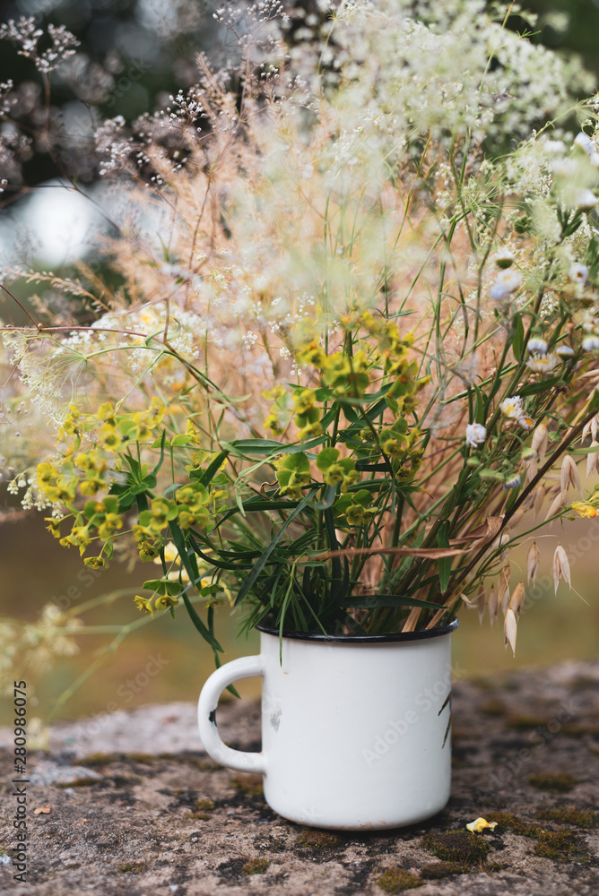 Beautiful field flowers, rural bouquet in white metal cup Beautiful field flowers, rural bouquet in white metal cup