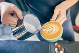 professional service at cafe concept. Barista Making of cafe latte art. pouring milk in glass of fresh made coffee. Milk and coffee toned picture. Hand of Barista making latte or cappuccino