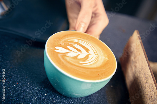 barista serving coffee in coffee house. Woman giving latte or cappuchino to customer behind the counter. Restaurant Coffee Shop Concept. Toned picture. Copy space. Fresh made coffee