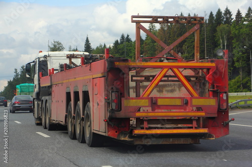 Heavy panel truck with semi-trailer rides on the highway on a summer day, logistics in the construction business