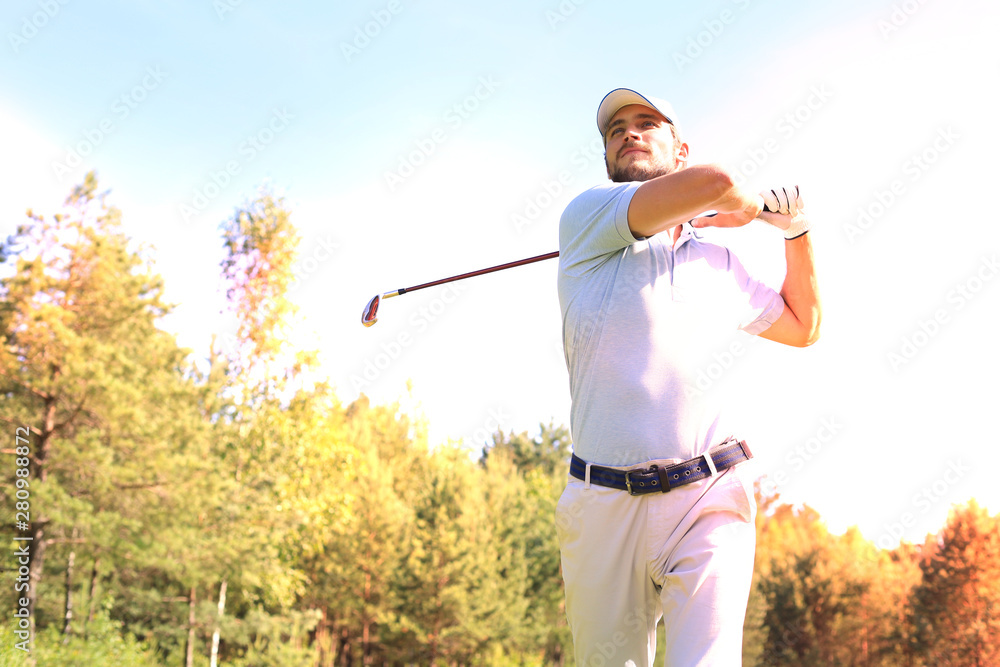 Golfer hitting golf shot with club on course while on summer vacation. Golfer hitting golf shot with club on course while on summer vacation.