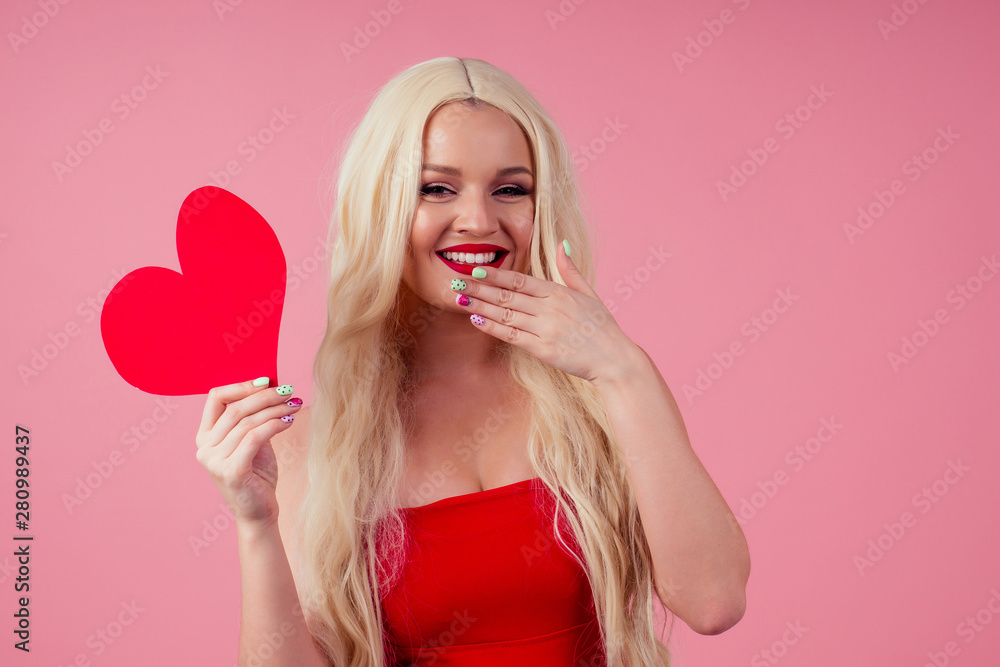 Closeup portrait of beautiful blond girl holding in hands paper heart and send kiss air isolated on pink background, Valentine day celebration Closeup portrait of beautiful blond girl holding in hands paper heart and send kiss air isolated on pink background, Valentine day celebration