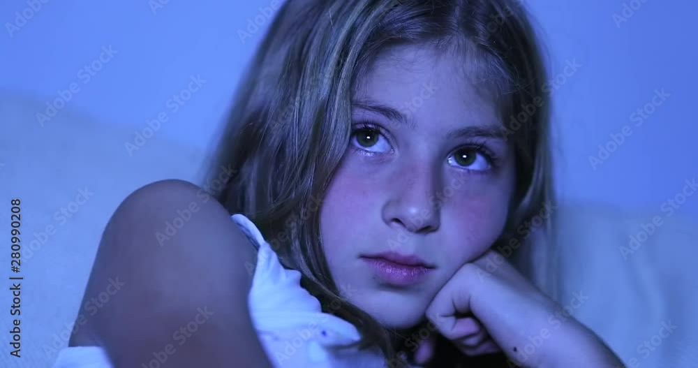 Child hypnotized by TV screen, little girl watching movie in the dark