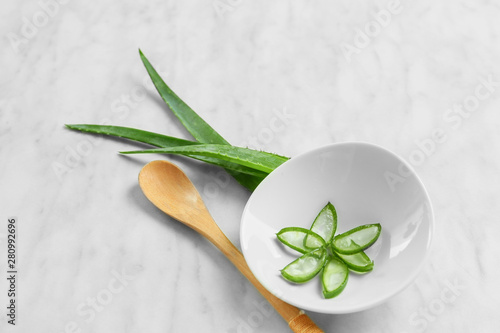 Bowl with aloe vera and spoon on light background