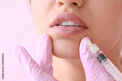 Young woman receiving injection of filler in lips, closeup