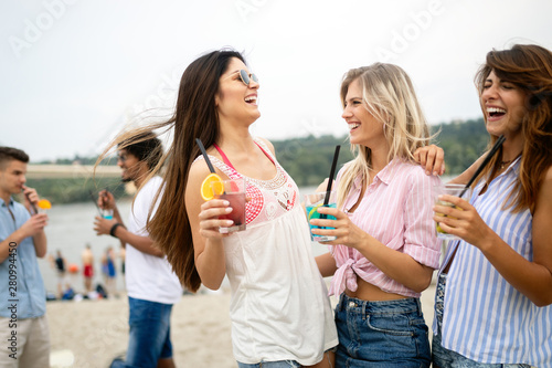 Group of friends hanging out with cocktails at the beach