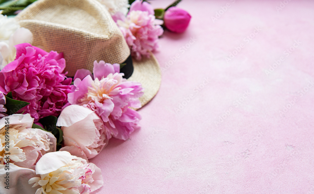 Pink peonies and hat on a pink concrete background