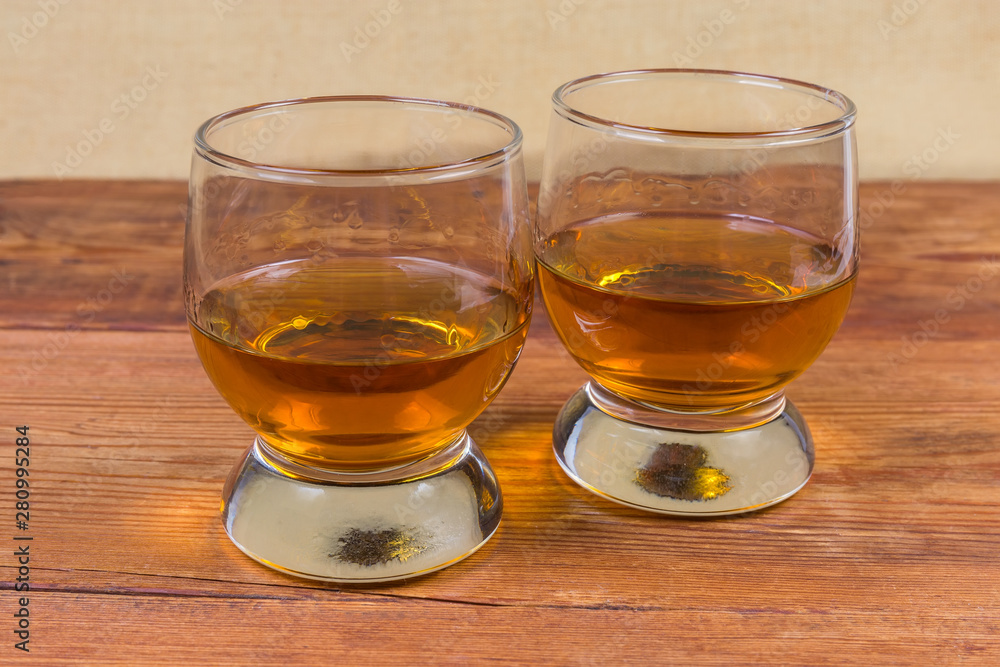 Two portions of brandy in brandy bowls on rustic table Two portions of brandy in brandy bowls on rustic table