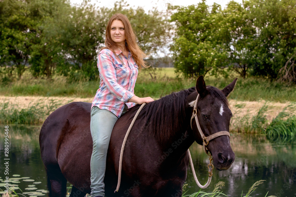 Fototapeta premium young woman sitting on her black horse