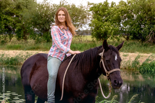 young woman sitting on her black horse