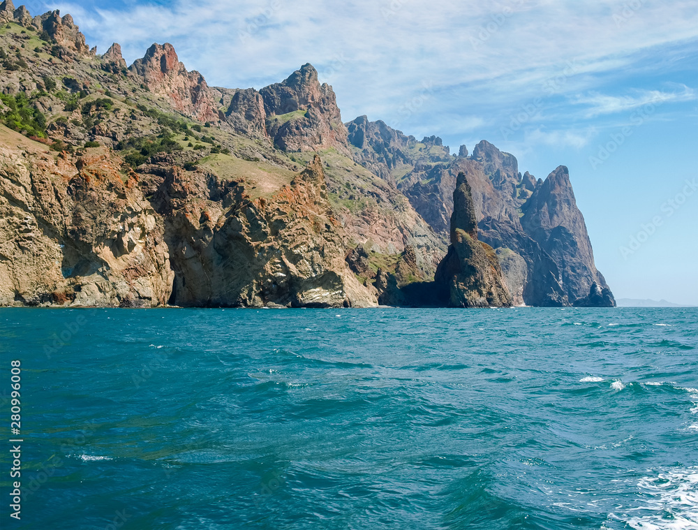 Coastal cliffs of volcanic origin on sea against of sky