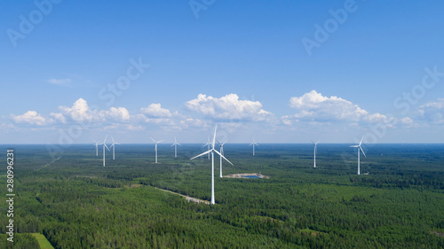 Wind power plant in the green field view and distant forest at summer evening. Concept of clean energy.