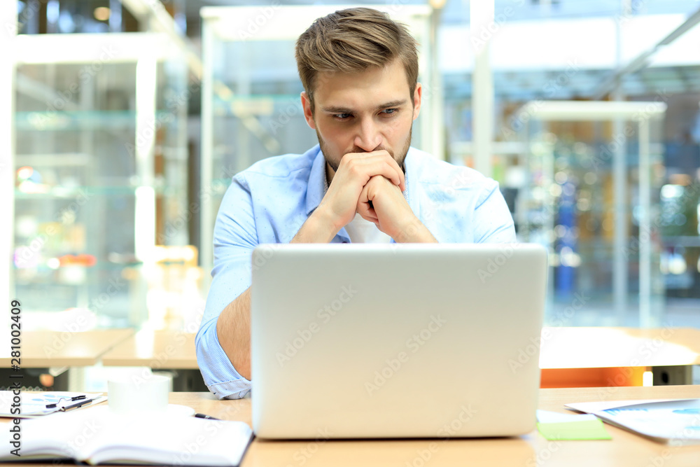 Portrait of young man sitting at his desk in the office. Portrait of young man sitting at his desk in the office.