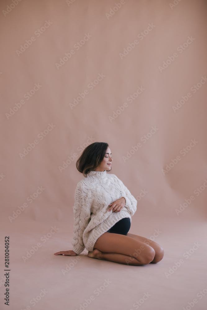 Obraz premium Pregnant woman with long hair in white sweater.