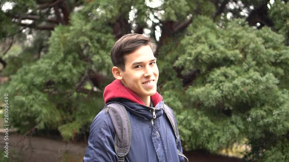 Portrait of beautiful student looking at camera and smiling on the city park background. Lifestyle authentic candid. Mixed european-asian race Portrait of beautiful student looking at camera and smiling on the city park background. Lifestyle authentic candid. Mixed european-asian race