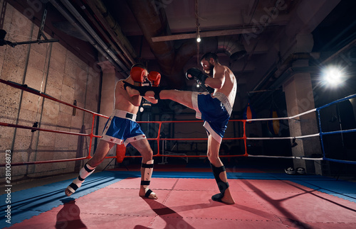 Two professional men boxers exercising kickboxing in the ring at the health club