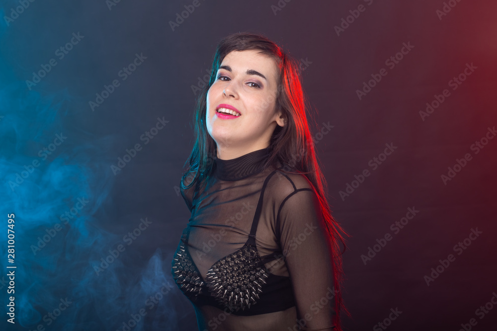 Alluring young beautiful brunette woman in a provocative dress posing on a dark background. Concept of seduction and sexual attractiveness.