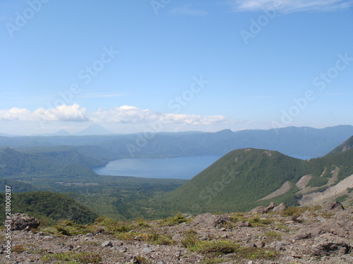 Wild mountains and lake Shikotsu in Hokkaido with blue sky and clouds and green trees in summer photo