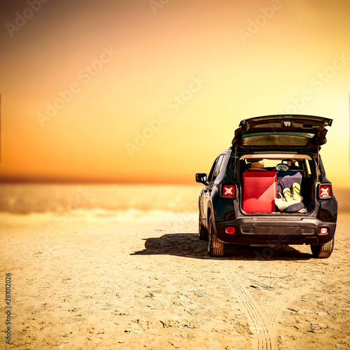 Black summer car on beach with suitcase and free space for your decoration. 