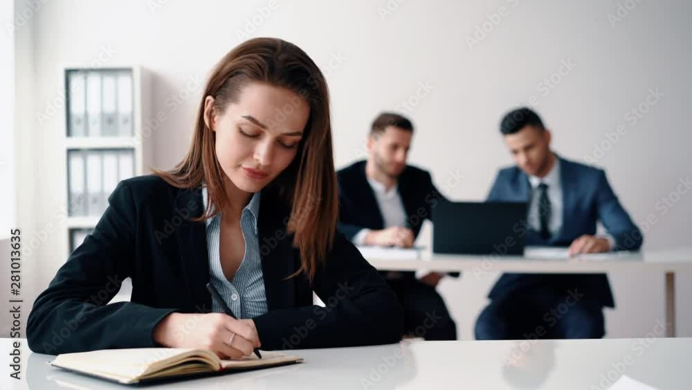 Pretty business woman sitting in office and making notes Pretty business woman sitting in office and making notes