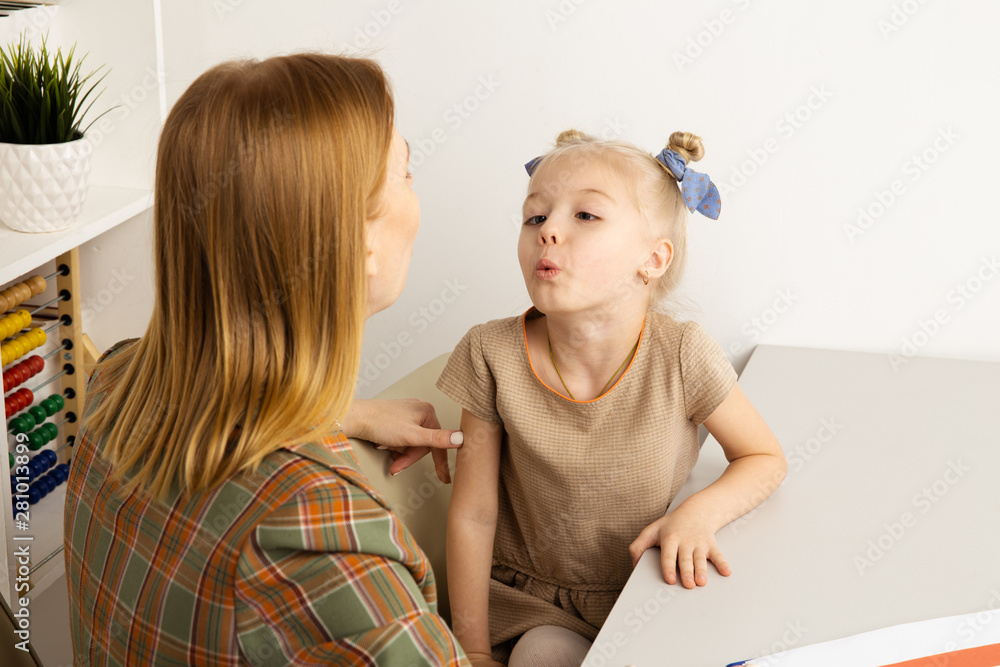 Cute girl with speech therapist in cabinet trainiing pronunciation Cute girl with speech therapist in cabinet trainiing pronunciation