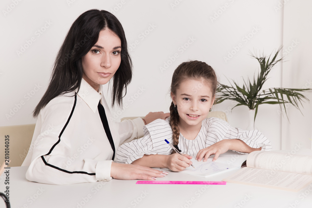 Mother and daughter sitting at the desk doing homework together Mother and daughter sitting at the desk doing homework together