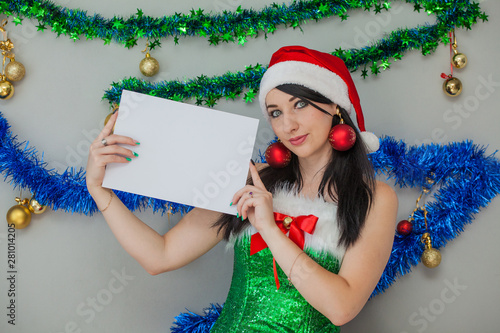 Sexy Santa Claus girlfriend with a white sign for the inscriptions in their hands. Emotional girl in a Christmas elf costume.