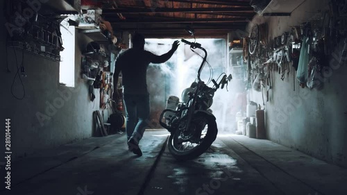 biker with a motorcycle in an atmospheric garage. a man sits on his iron horse and prepares to set off