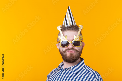 Crazy young positive hipster guy with a beard laughs happily on a yellow background with copy space. The concept of holidays and sales
