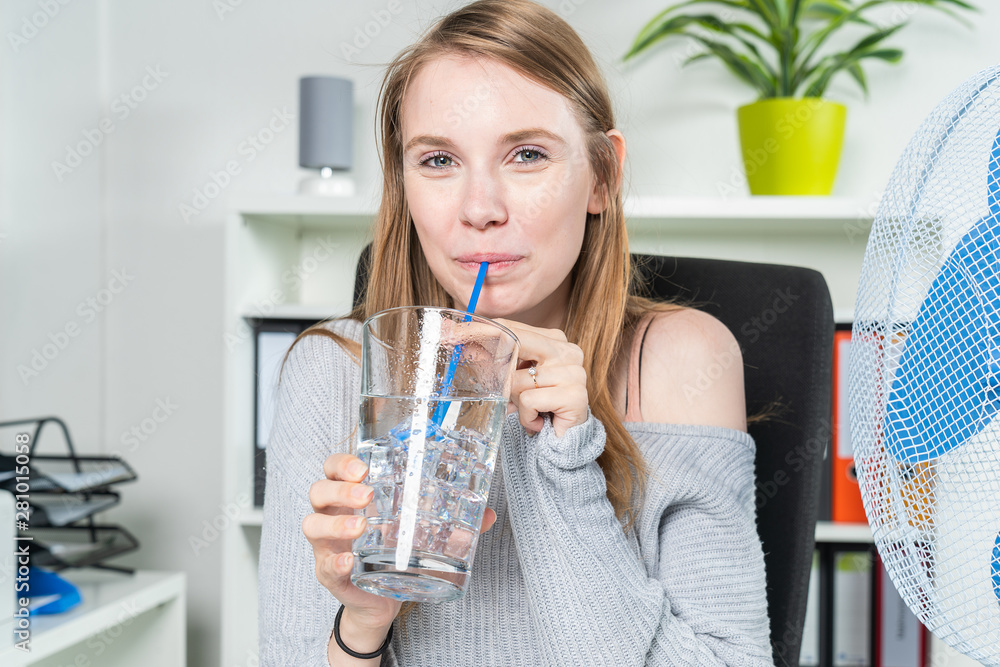 woman in the office cools off with a glass of ice water woman in the office cools off with a glass of ice water