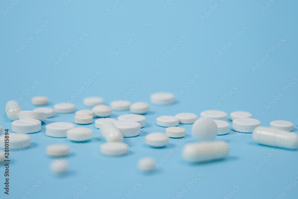 White medical pills on blue background.