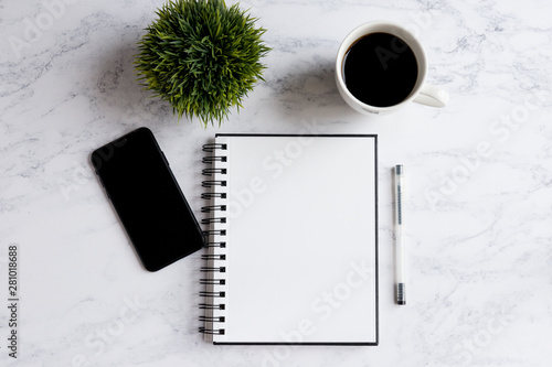 Notepad and pen, phone, coffee cup and plant on marble desk