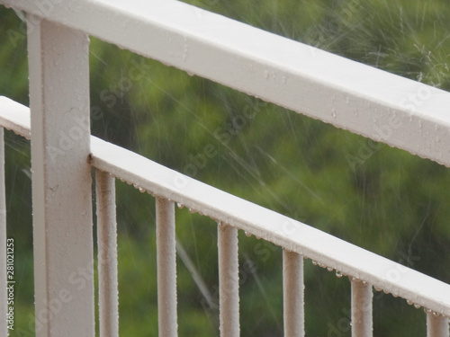 Lluvia que cae sobre una terraza y sobre una barandilla, lluvia de verano