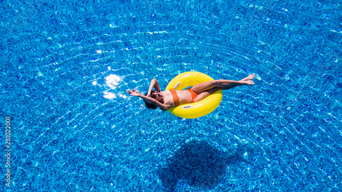 Beautiful woman relaxing on inflatable ring in blue swimming pool. © F8  \ Suport Ukraine